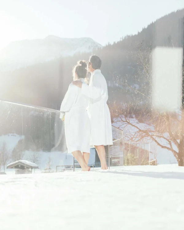 Wiesenhof am Achensee | Das Hotel in Pertisau Paar in Bademänteln genießt sonnige Winterlandschaft auf Balkon