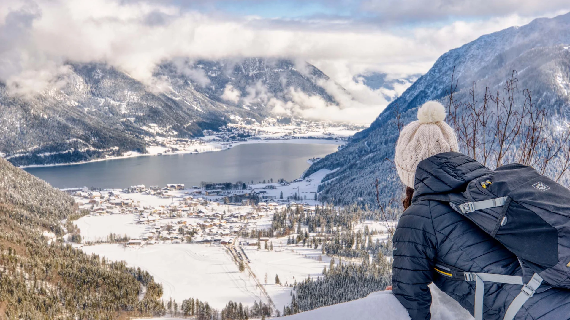 Das 4-Sterne-Hotel am Achensee: der Wiesenhof Frau mit Rucksack blickt auf verschneites Tal und See in den Bergen
