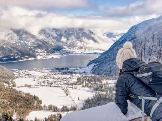 Wiesenhof am Achensee | Das Hotel in Pertisau Frau mit Rucksack blickt auf verschneites Tal und See in den Bergen