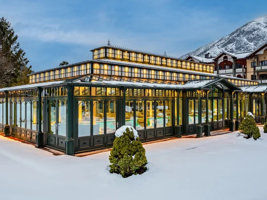 Home Illuminated glass pavilion in snowy winter landscape with mountains in background