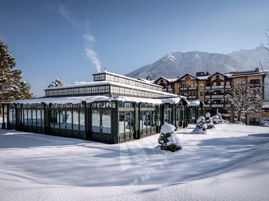 Home Snow-covered historic building with mountains in the background under clear sky