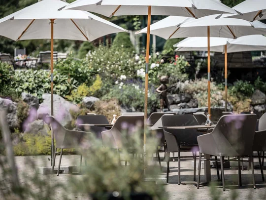 Wiesenhof in Pertisau: the Entner family and team Empty patio with white umbrellas and chairs in a garden