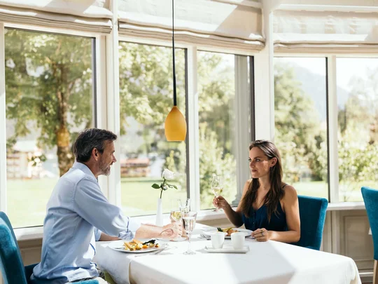 Wiesenhof am Achensee | Das Hotel in Pertisau Paar beim Mittagessen in einem hellen Restaurant mit großen Fenstern und Naturblick