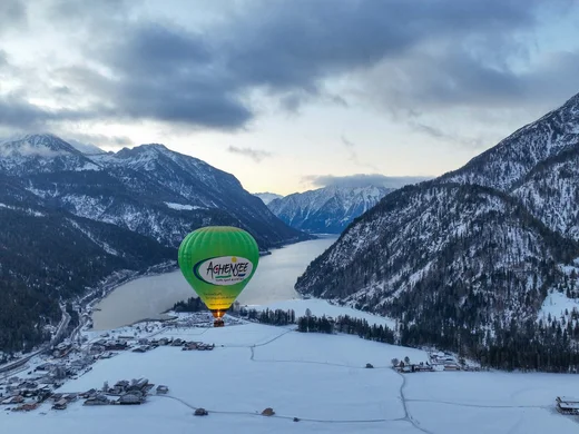 Discover Lake Achensee Hot air balloon over snowy valley and mountains in winter