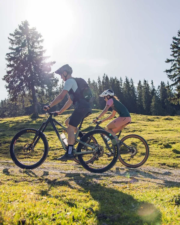 Wiesenhof am Achensee | Das Hotel in Pertisau Zwei Radfahrer fahren auf einem sonnigen Waldweg mit grüner Wiese