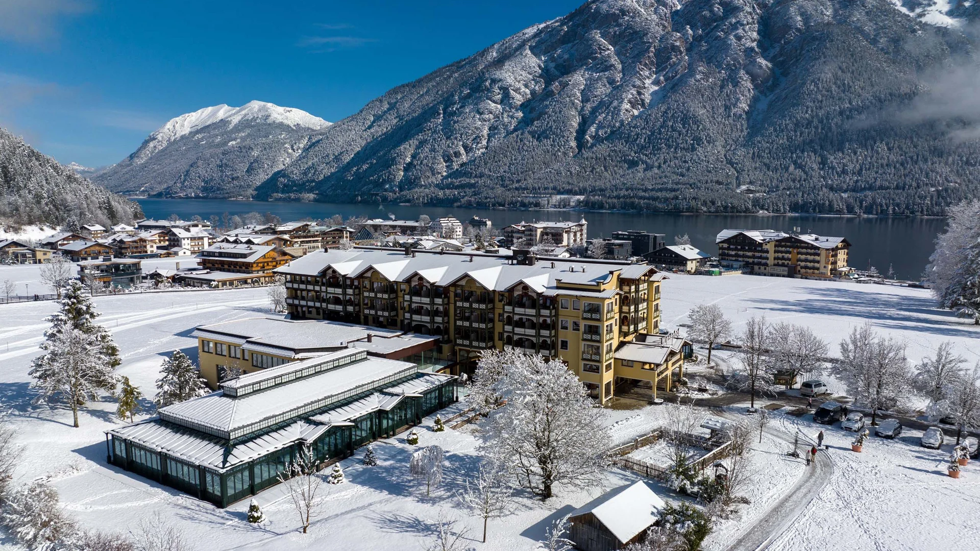 Wiesenhof in Pertisau: the Entner family and team Snow-covered Alpine village and lake with clear blue sky in winter