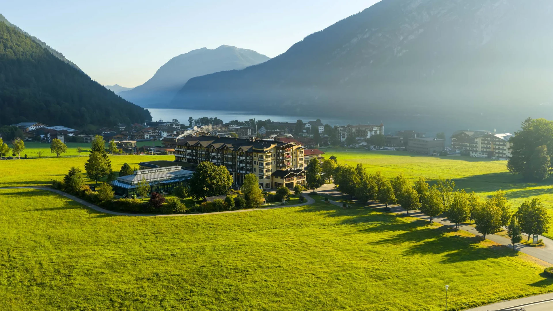 Das 4-Sterne-Hotel am Achensee: der Wiesenhof Grünes Tal mit Hotels, Bergen und See im Morgendunst