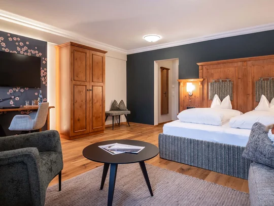 Das 4-Sterne-Hotel am Achensee: der Wiesenhof Gemütliches Hotelzimmer mit Doppelbett, Holzschrank und Fernseher an der Wand