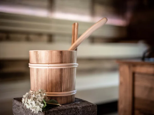 Eure Fragen – unsere Wiesenhof Antworten Traditioneller Holzsaunabecher mit Schöpfkelle und Blume auf Stein