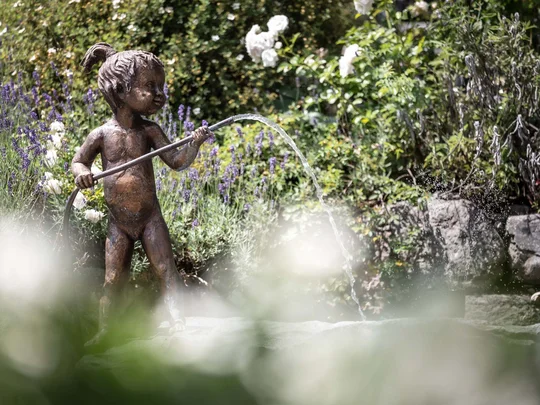Wiesenhof in Pertisau: the Entner family and team Bronze statue of child holding a water hose in a garden with flowers