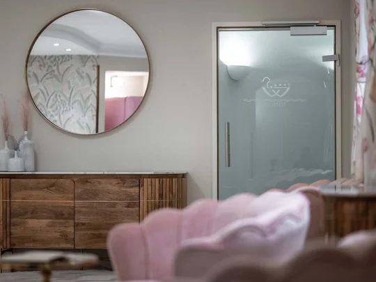 Wiesenhof – your spa hotel in Tyrol Modern interior with round mirror, wooden cabinet, and glass shower door