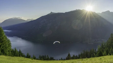 Wiesenhof from all perspectives Paraglider over a lake with mountains and sun in the sky