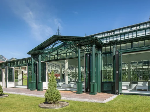 Wiesenhof – your spa hotel in Tyrol Green historic greenhouse with white furniture and mountains in the background