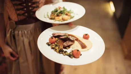 Wiesenhof from all perspectives Waitress serving two plates of gourmet food in traditional dress