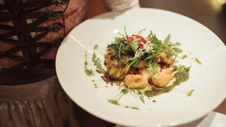 Wiesenhof from all perspectives Person holding a plate with gnocchi and green leafy garnish