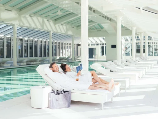 Wiesenhof – your spa hotel in Tyrol Couple relaxing in bathrobes on lounge chairs beside indoor swimming pool