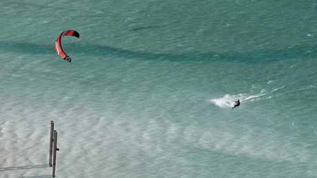 Wiesenhof from all perspectives Kitesurfer with red kite on blue water on a sunny day