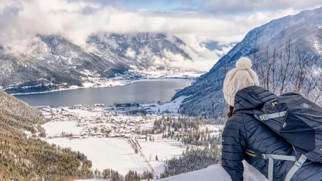 Wiesenhof from all perspectives Woman with backpack overlooking snowy valley and lake in the mountains