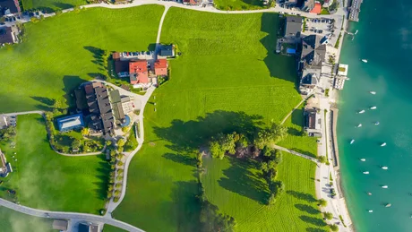 Wiesenhof from all perspectives Aerial view of a green field next to a lake and buildings in sunlight