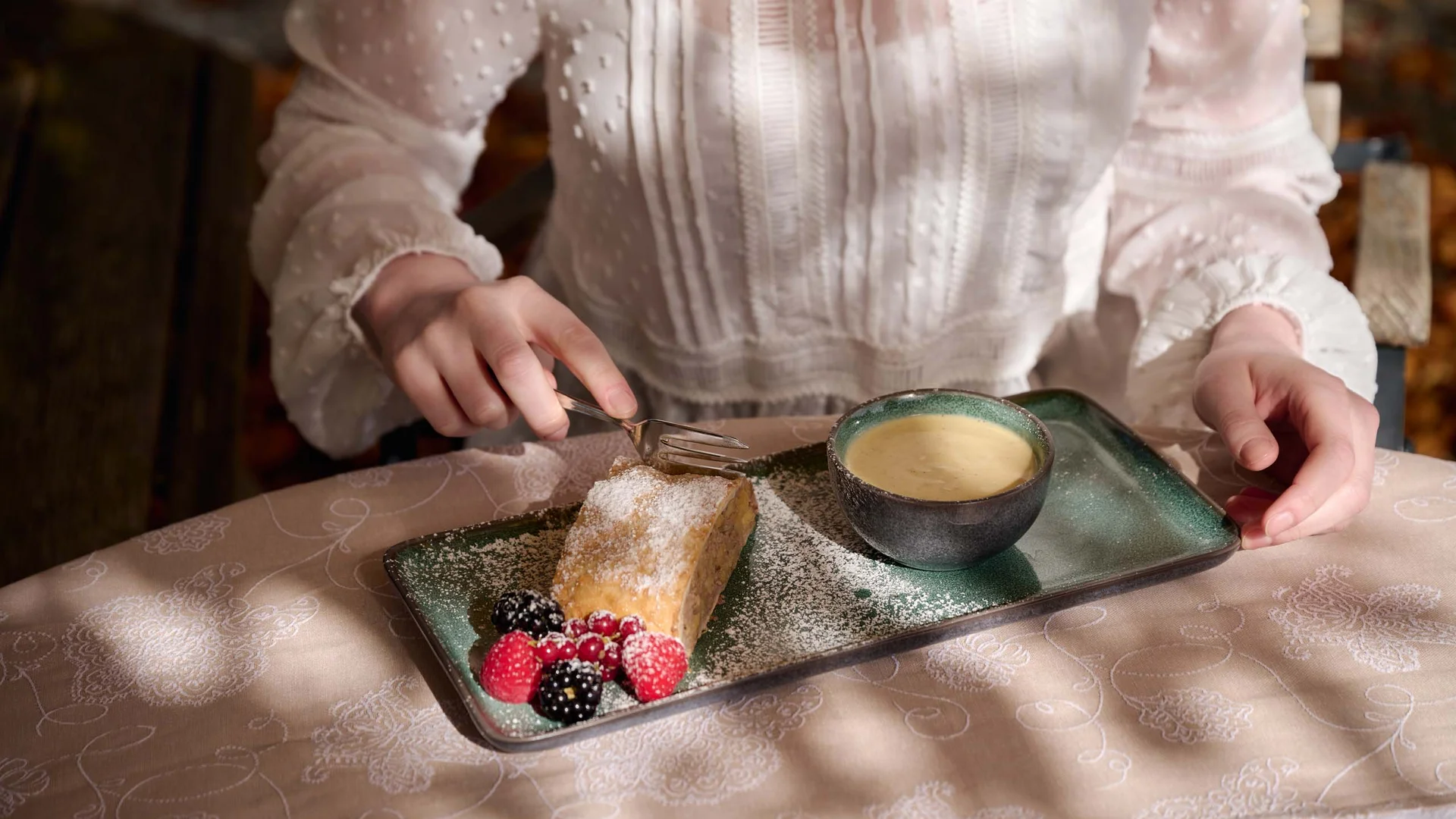 Cuisine at Wiesenhof: restaurant in Pertisau Person in white blouse eating cake with berries and coffee on green plate