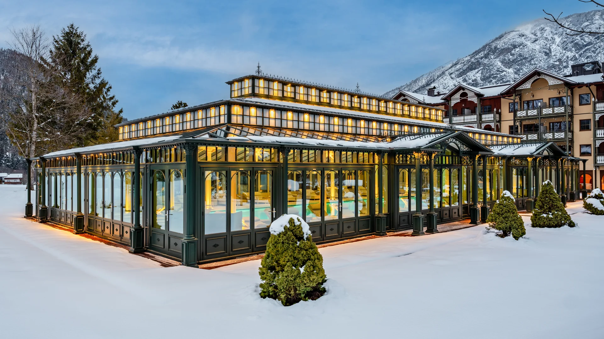 Wiesenhof – your spa hotel in Tyrol Illuminated glass pavilion in snowy winter landscape with mountains in background