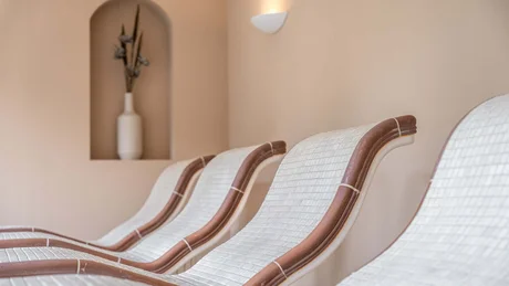 Wiesenhof from all perspectives Four white lounge chairs with brown accents against beige wall with vase