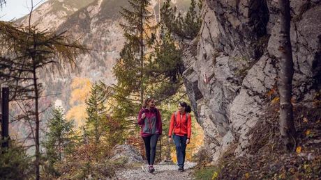 Wiesenhof from all perspectives Two women hiking on a mountain trail with rocks and autumn trees