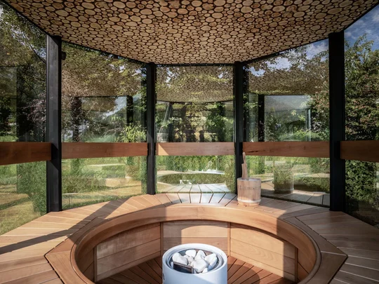 Wiesenhof – your spa hotel in Tyrol Modern wooden sauna interior with glass walls and log-patterned wooden ceiling