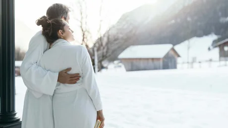 Wiesenhof from all perspectives Couple in bathrobes hugging outside in snowy landscape with cabins