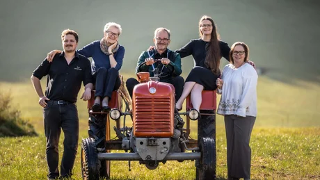 Wiesenhof from all perspectives Five people standing and sitting on a red tractor in a grassy field