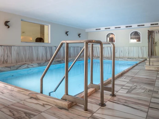 Wiesenhof – your spa hotel in Tyrol Small indoor pool with marble tiles and stainless steel railings