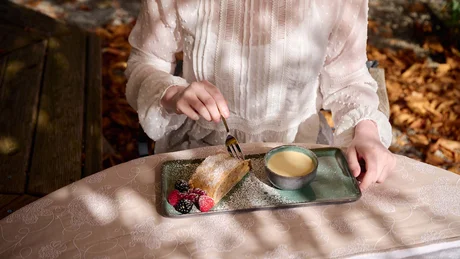 Wiesenhof from all perspectives Person in white blouse eating cake with berries and drinking coffee outdoors