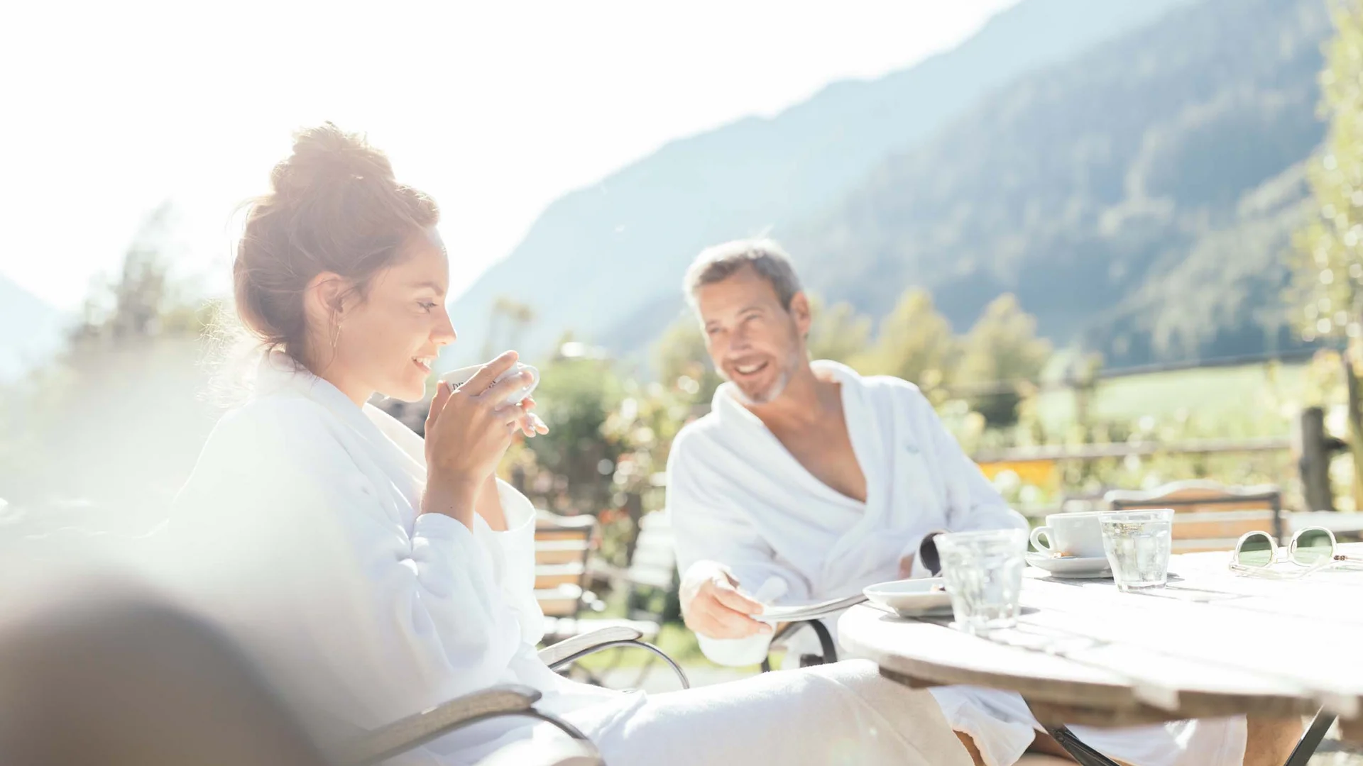 Wiesenhof – your spa hotel in Tyrol Couple in bathrobes enjoying drinks outdoors with mountain view