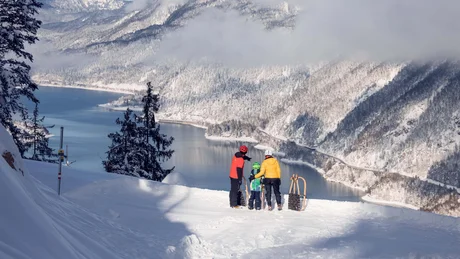 Wiesenhof from all perspectives Three people with sleds overlooking snowy mountains and a river