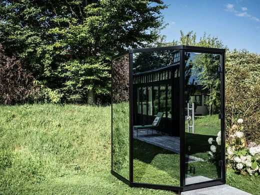Wiesenhof – your spa hotel in Tyrol Reflective black glass pavilion in garden on a sunny day