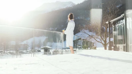 Wiesenhof from all perspectives Woman in bathrobe on snowy balcony overlooking mountains in the morning