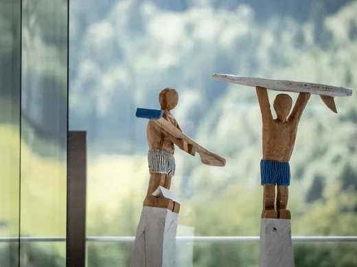 Wiesenhof – your spa hotel in Tyrol Wooden figures in swim trunks, one holding a board above head
