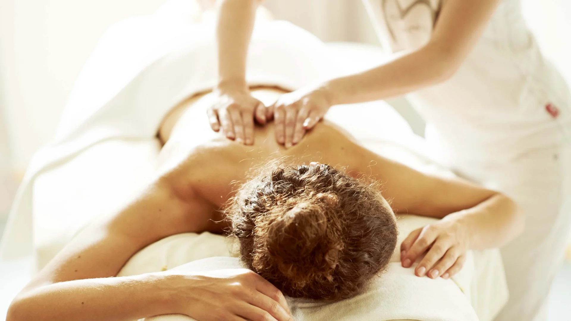 Wiesenhof – your spa hotel in Tyrol Person getting a back massage in a bright spa setting