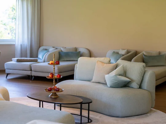 Wiesenhof – your spa hotel in Tyrol Modern living room with comfortable sofas, cushions, and a decorative table with fruit