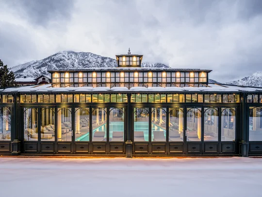 Wiesenhof – your spa hotel in Tyrol Lit greenhouse with indoor pool in snowy mountain area at dusk