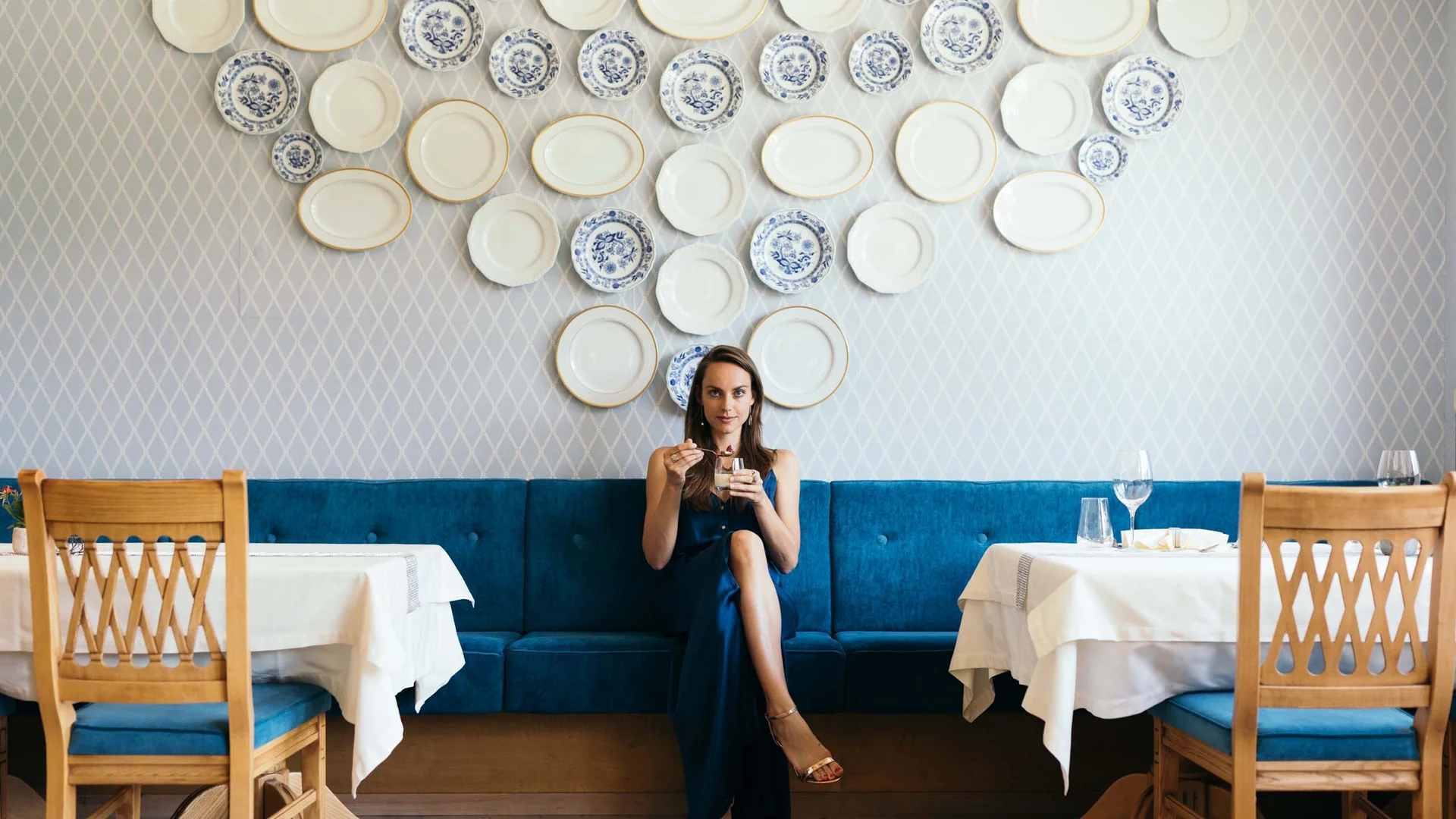 Cuisine at Wiesenhof: restaurant in Pertisau Woman in blue dress sitting in a restaurant with decorative plates on the wall