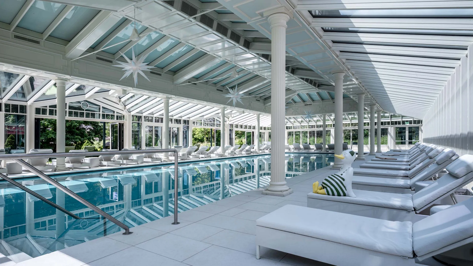 Wiesenhof – your spa hotel in Tyrol Indoor pool with white loungers and glass roof in sunlit room