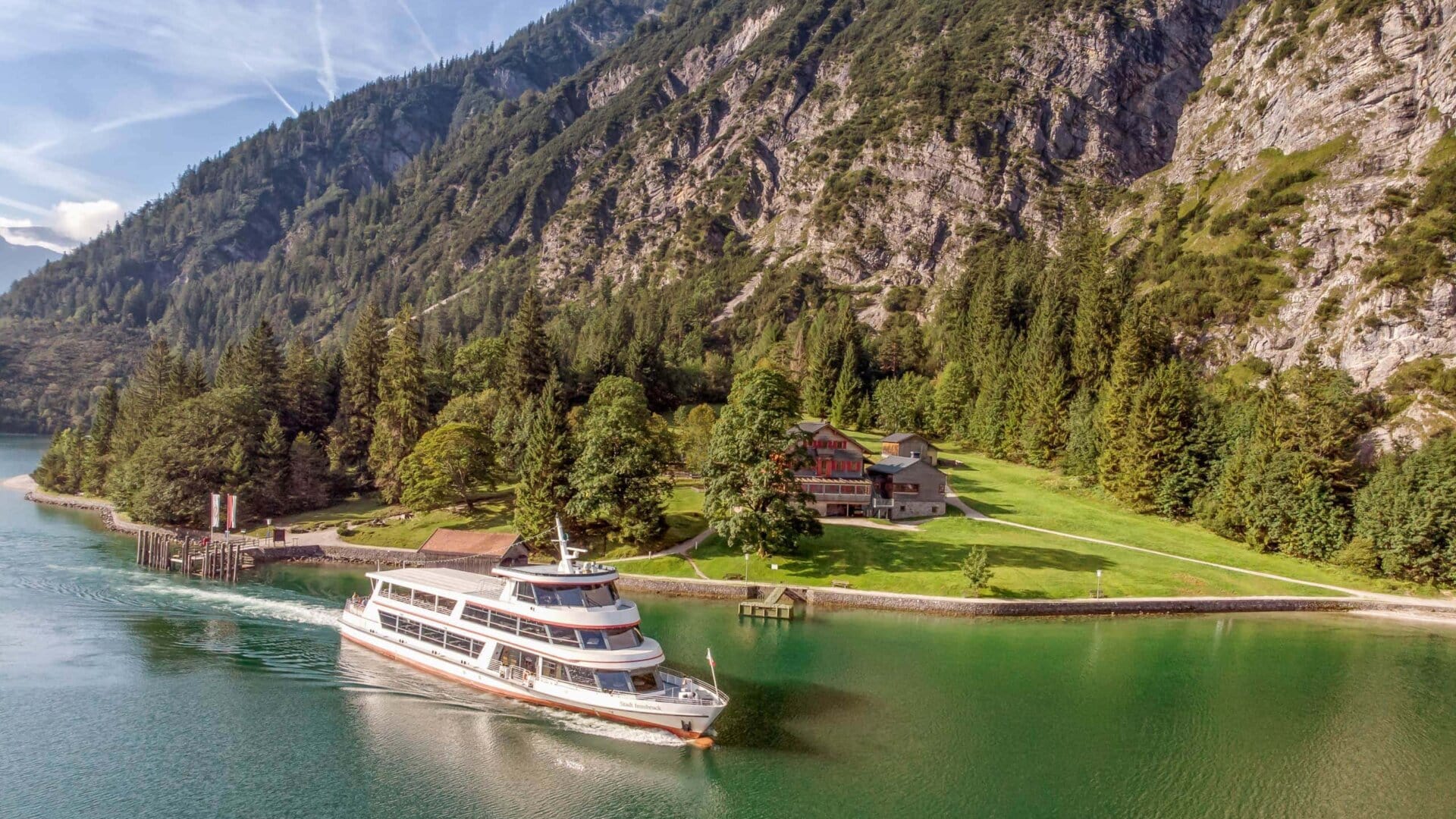 Schiff fährt auf ruhigem, grünem Wasser.