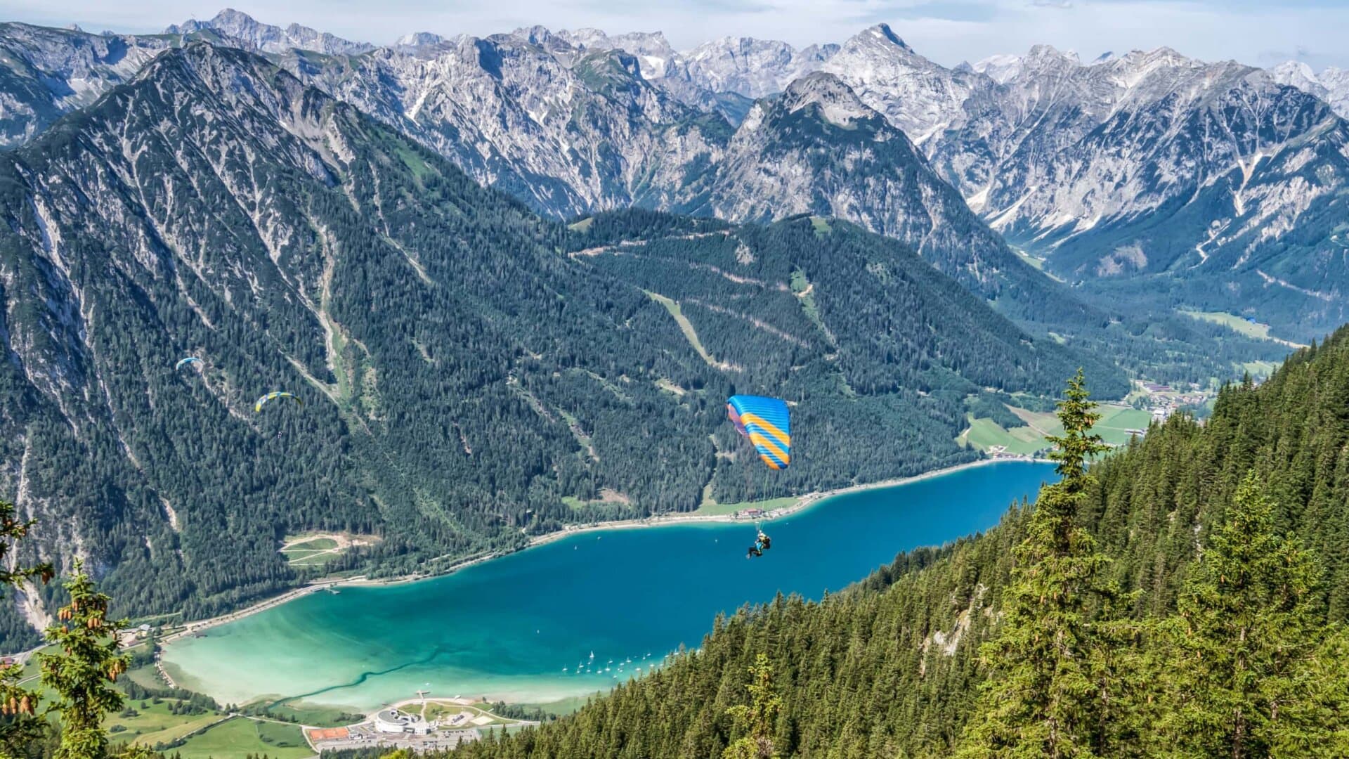 Paraglider über grünem See und Bergen